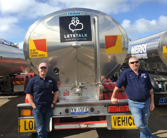 Two truckies standing with Lets talk banner on the truck